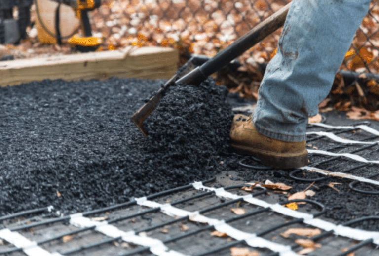 a contractor shoveling asphalt material for a heated driveway